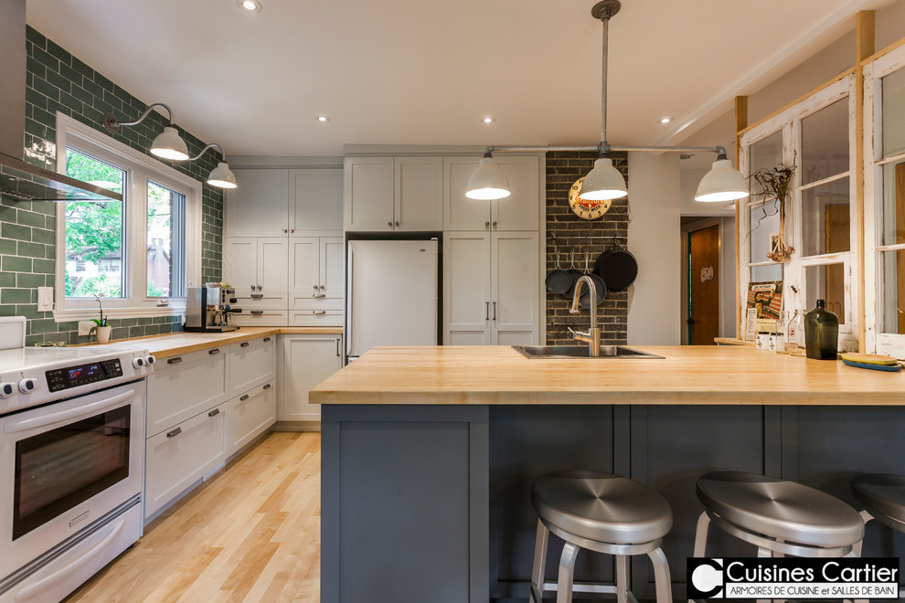 Example of a large transitional galley medium tone wood floor open concept kitchen design in Montreal with a single-bowl sink, shaker cabinets, gray cabinets, wood countertops, green backsplash, ceramic backsplash, white appliances and an island