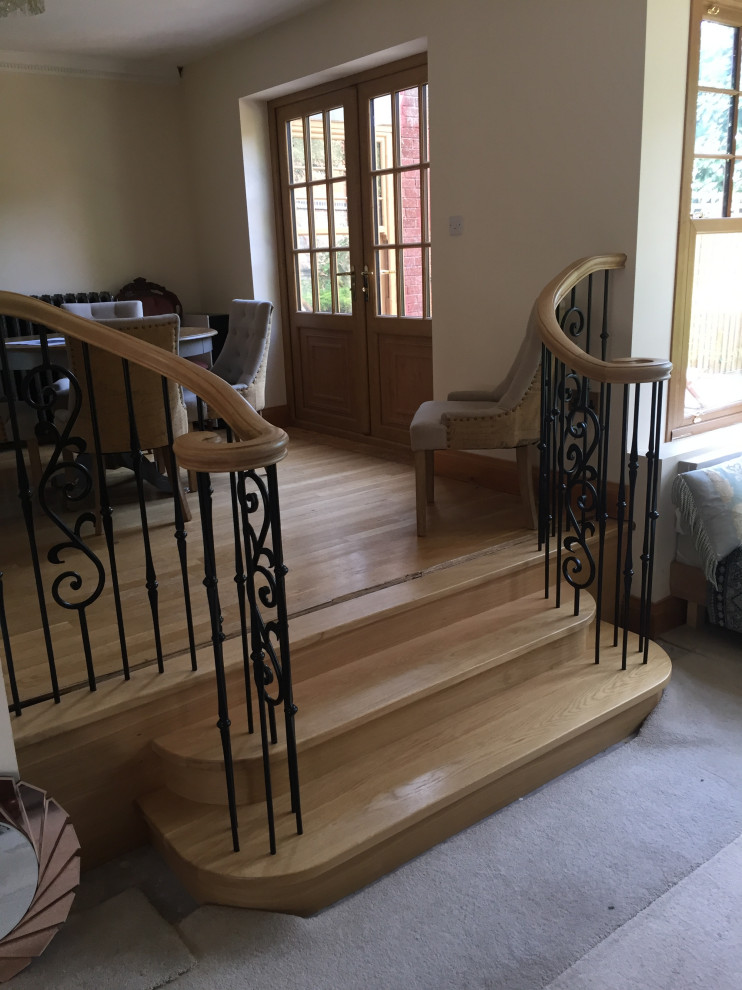 Inspiration for a small timeless wooden curved metal railing staircase remodel in Other with wooden risers