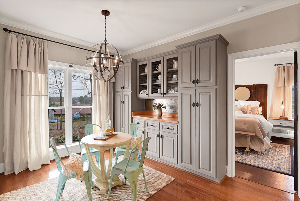 Design ideas for an arts and crafts u-shaped eat-in kitchen in Other with raised-panel cabinets, grey cabinets, wood benchtops, metallic splashback, mirror splashback, stainless steel appliances, medium hardwood floors, brown floor and brown benchtop.