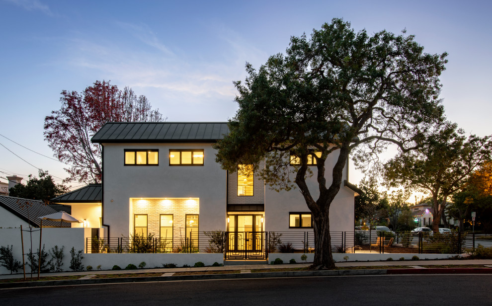 Mid-sized contemporary stucco white house exterior in Los Angeles with a hip roof, a metal roof and a black roof.