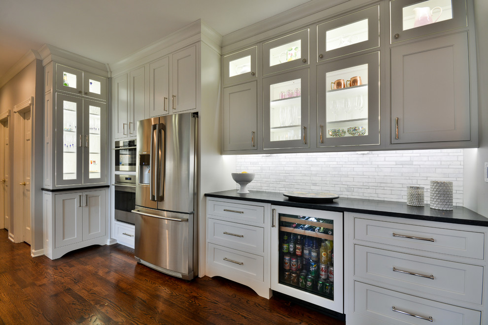 Example of a large transitional u-shaped dark wood floor and brown floor eat-in kitchen design in Chicago with an undermount sink, recessed-panel cabinets, white cabinets, soapstone countertops, gray backsplash, marble backsplash, stainless steel appliances and an island