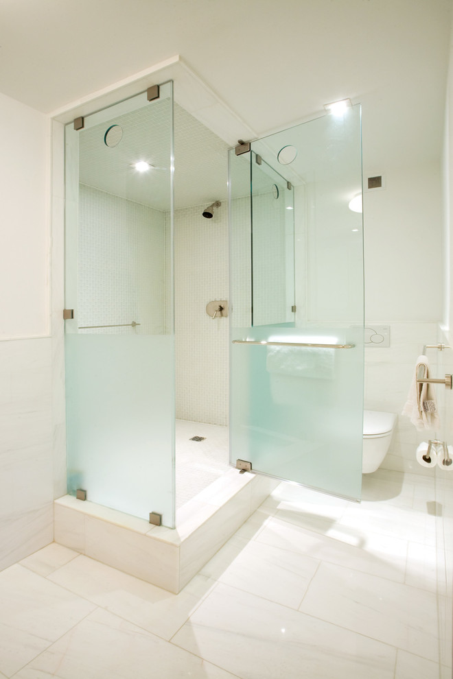 Inspiration for a mid-sized modern master bathroom in New York with a corner shower, a wall-mount toilet, white tile, marble, white walls, marble floors, a trough sink, marble benchtops, white floor and a hinged shower door.