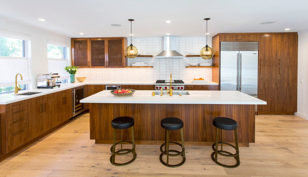 Photo of a contemporary l-shaped kitchen in Los Angeles with an undermount sink, flat-panel cabinets, medium wood cabinets, white splashback, stainless steel appliances, light hardwood floors and with island.