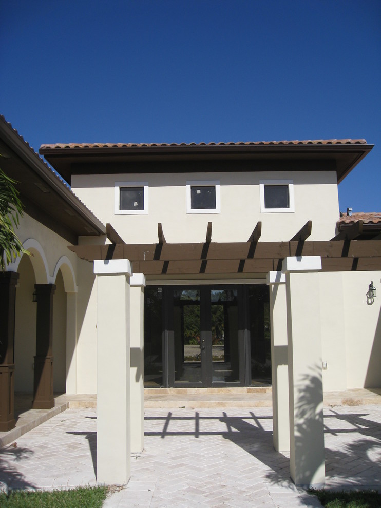 Inspiration for a large mediterranean one-storey stucco beige house exterior in Miami with a hip roof and a tile roof.
