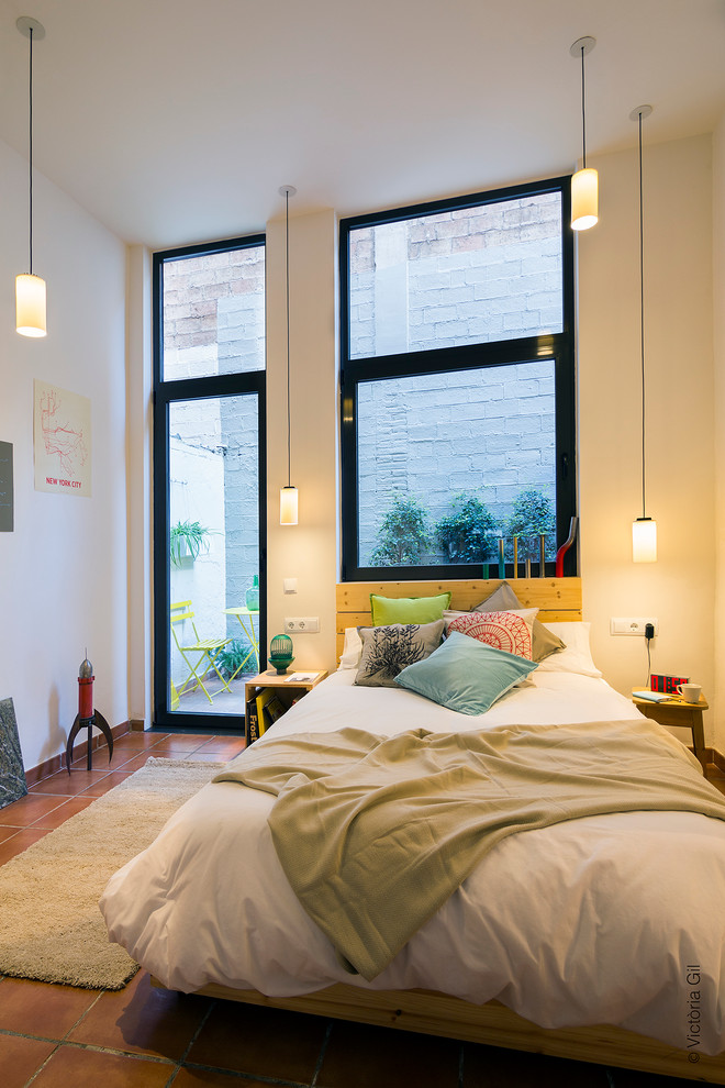 Design ideas for a small modern loft-style bedroom in Barcelona with white walls, terra-cotta floors and no fireplace.