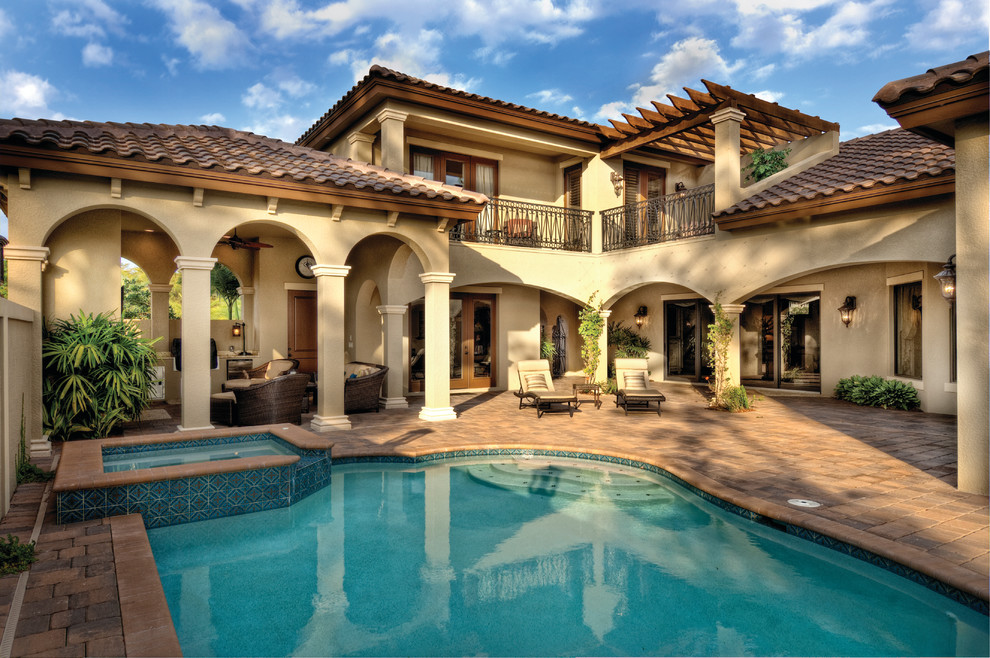 This is an example of a large mediterranean two-storey stucco beige exterior in Miami with a hip roof.