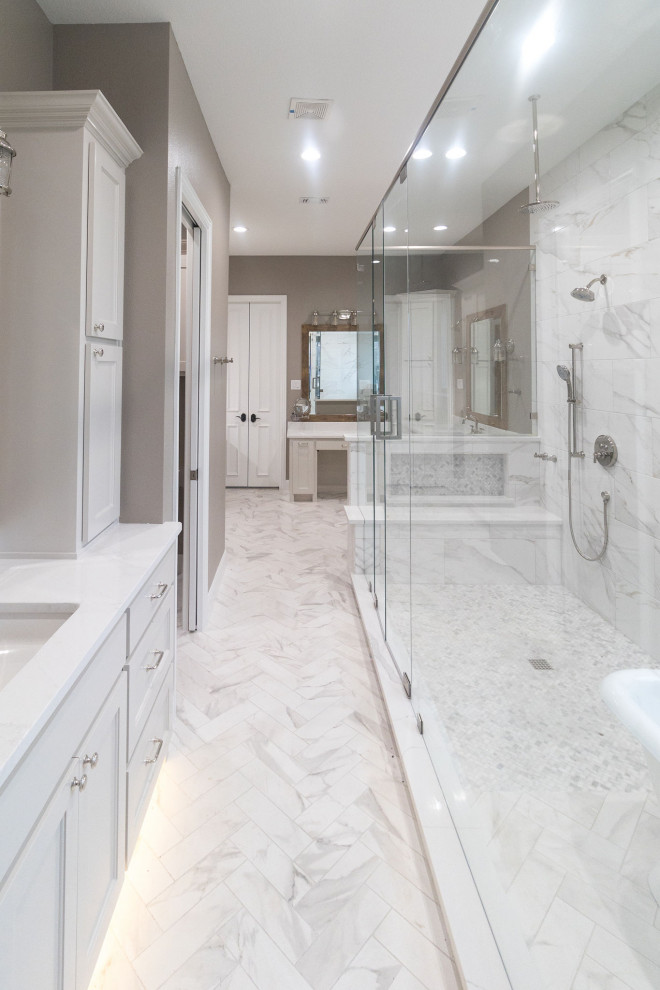 Expansive traditional ensuite wet room bathroom in Dallas with shaker cabinets, white cabinets, a freestanding bath, white tiles, marble tiles, porcelain flooring, a submerged sink, engineered stone worktops, white floors, a hinged door, white worktops, a shower bench, double sinks and a built in vanity unit.