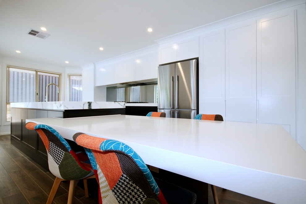 Inspiration for a large modern single-wall open plan kitchen in Sydney with an undermount sink, shaker cabinets, black cabinets, marble benchtops, grey splashback, mirror splashback, stainless steel appliances, medium hardwood floors, with island, brown floor, white benchtop and recessed.