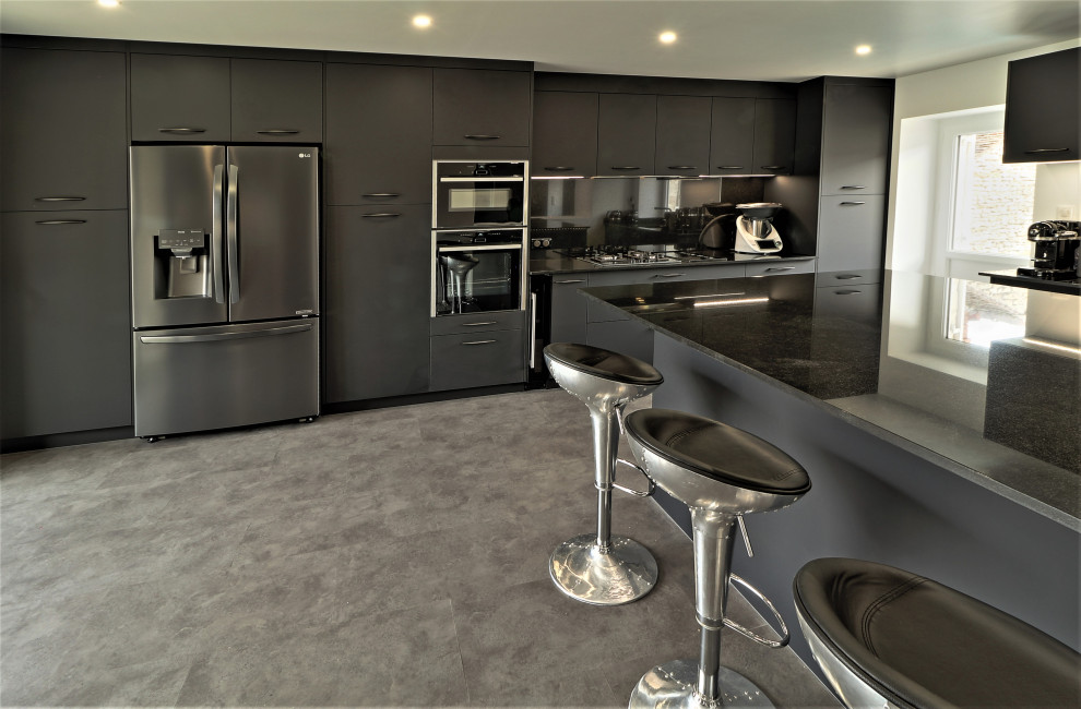 Expansive contemporary galley eat-in kitchen in Other with an undermount sink, flat-panel cabinets, black cabinets, quartzite benchtops, black splashback, granite splashback, stainless steel appliances, laminate floors, with island, grey floor and black benchtop.