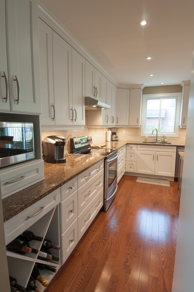 Example of a large transitional u-shaped medium tone wood floor enclosed kitchen design in Toronto with a double-bowl sink, shaker cabinets, white cabinets, granite countertops, beige backsplash, ceramic backsplash, stainless steel appliances and an island