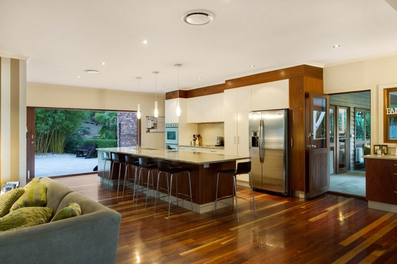 Inspiration for a large modern galley open plan kitchen in Brisbane with a double-bowl sink, flat-panel cabinets, white cabinets, granite benchtops, white splashback, stone tile splashback, stainless steel appliances, dark hardwood floors and with island.