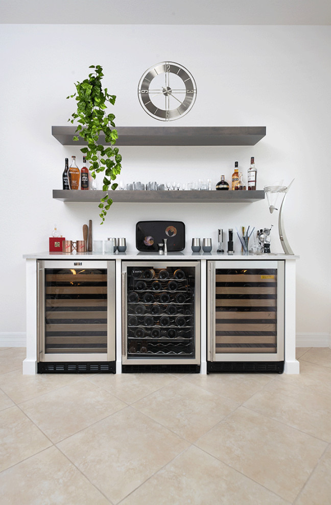 Mid-sized contemporary single-wall home bar in Miami with glass-front cabinets, white cabinets, quartz benchtops, porcelain floors, beige floor, white benchtop and no sink.