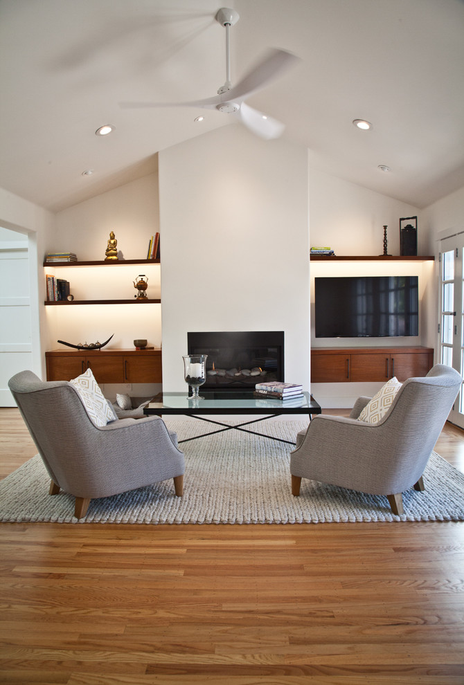 Photo of a mid-sized contemporary open concept family room in San Francisco with white walls, light hardwood floors, a ribbon fireplace, a plaster fireplace surround, a wall-mounted tv and brown floor.