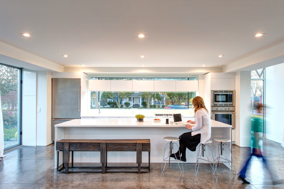 Inspiration for a modern kitchen in Other with an integrated sink, flat-panel cabinets, white cabinets, solid surface benchtops, stainless steel appliances, concrete floors, with island, grey floor, white benchtop and window splashback.
