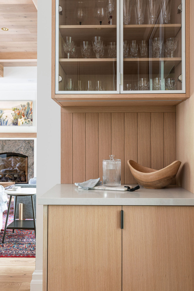 Exempel på ett mellanstort modernt vit linjärt vitt kök med öppen planlösning, med en integrerad diskho, släta luckor, skåp i ljust trä, bänkskiva i kvartsit, vitt stänkskydd, stänkskydd i mosaik, rostfria vitvaror, mellanmörkt trägolv, en köksö och brunt golv