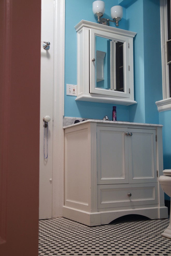 This is an example of an eclectic 3/4 bathroom in New York with shaker cabinets, white cabinets, a one-piece toilet, white tile, mosaic tile, blue walls and ceramic floors.