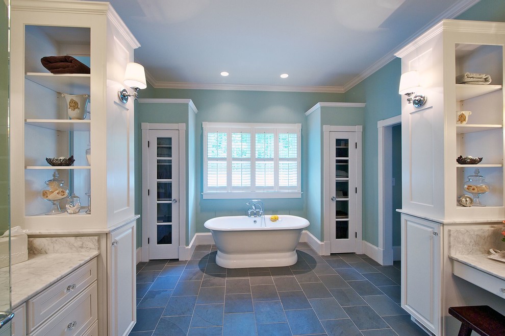 Inspiration for a mid-sized traditional master wet room bathroom in Orange County with recessed-panel cabinets, white cabinets, a freestanding tub, white tile, stone slab, blue walls, slate floors, marble benchtops, an undermount sink and a hinged shower door.
