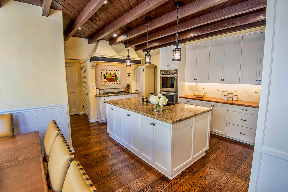 Photo of a large traditional u-shaped eat-in kitchen in Los Angeles with a farmhouse sink, shaker cabinets, white cabinets, quartz benchtops, white splashback, cement tile splashback, stainless steel appliances, painted wood floors and with island.