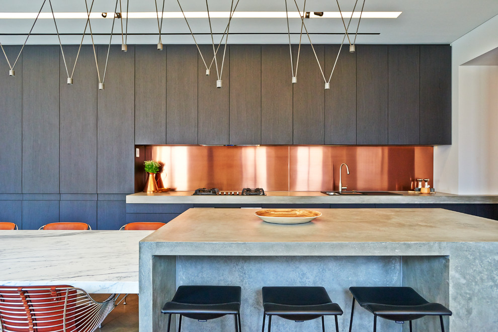 Photo of an industrial kitchen in Adelaide with a double-bowl sink, flat-panel cabinets, dark wood cabinets, concrete benchtops, metallic splashback, metal splashback, medium hardwood floors and with island.