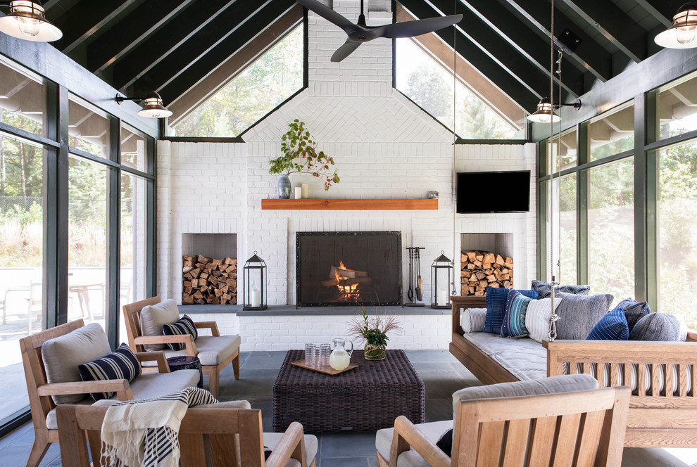 Sunroom - large farmhouse screened-in, slate floor and gray floor sunroom idea with a roof extension, a standard fireplace, a brick fireplace and a skylight