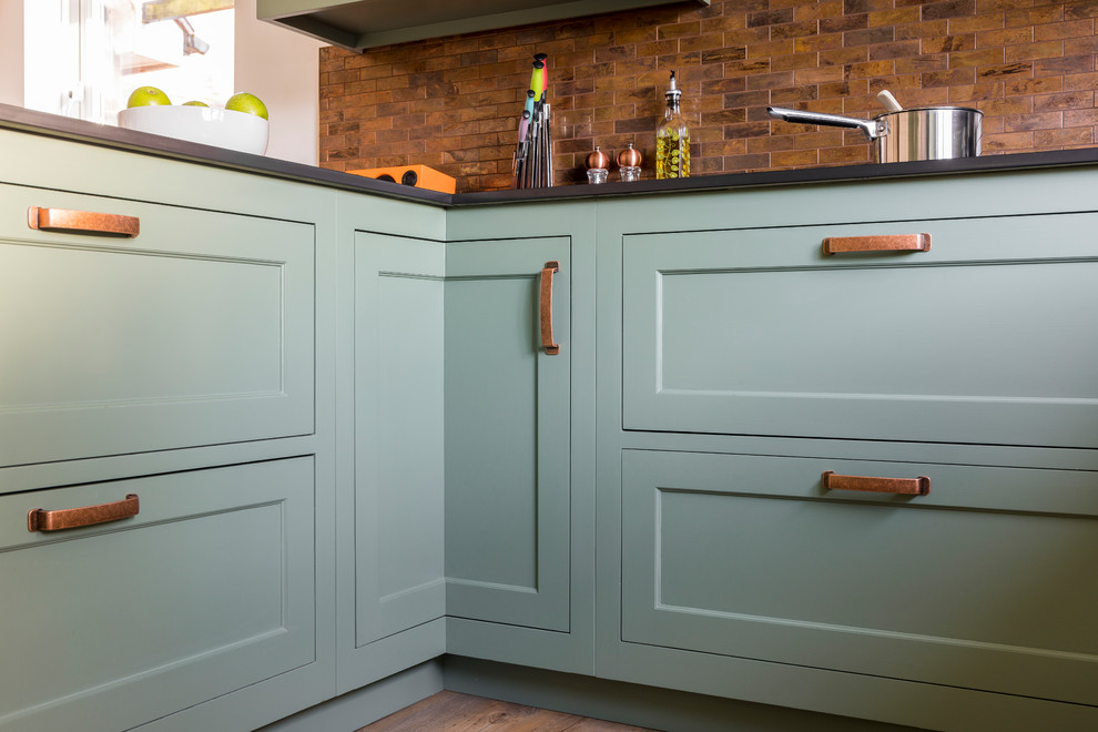 Inspiration for a mid-sized traditional u-shaped eat-in kitchen in Kent with a farmhouse sink, shaker cabinets, green cabinets, quartz benchtops, metal splashback, linoleum floors, a peninsula and green floor.