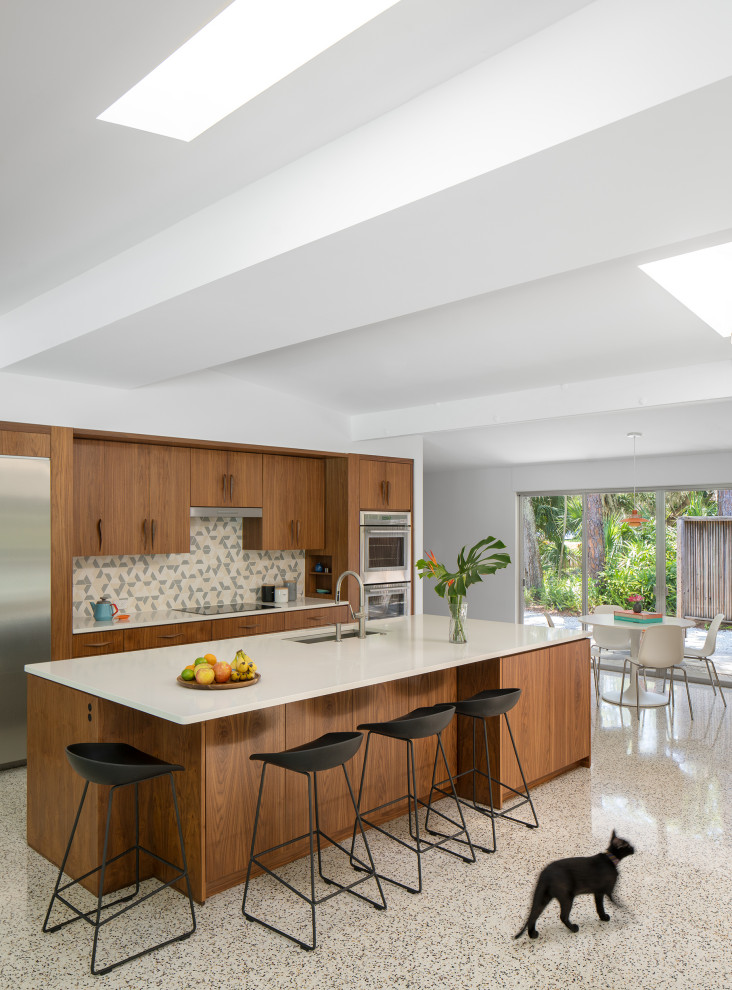 Inspiration for a large midcentury single-wall kitchen/diner in Tampa with flat-panel cabinets, dark wood cabinets, engineered stone countertops, multi-coloured splashback, ceramic splashback, stainless steel appliances, terrazzo flooring, an island and grey worktops.