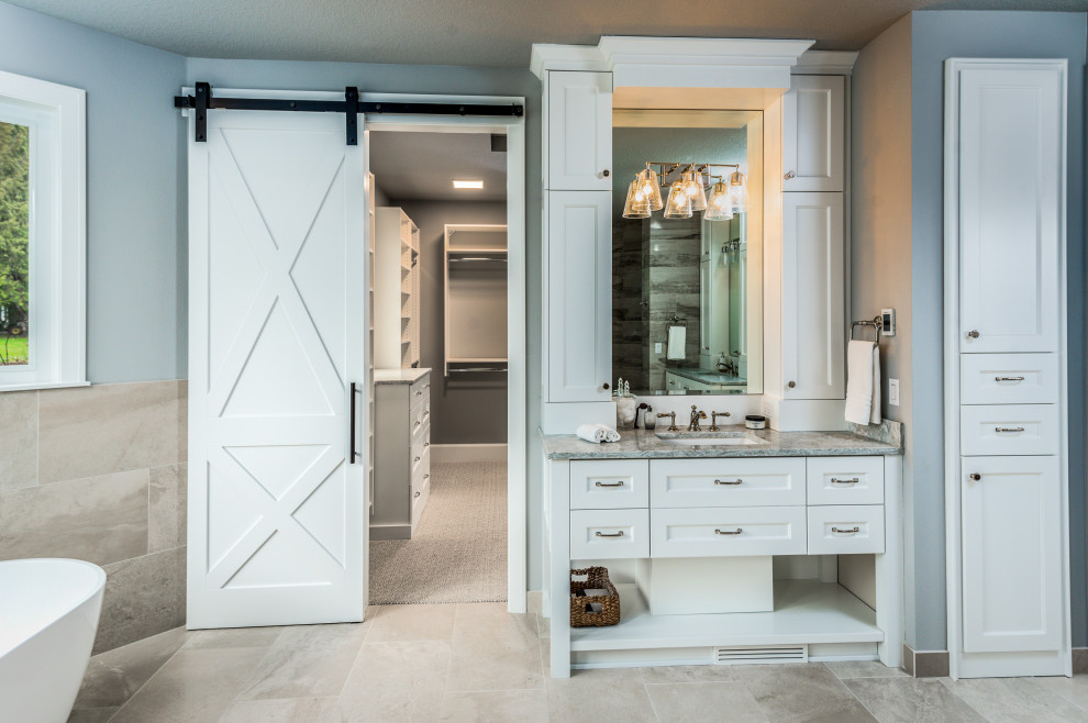 This is an example of a large transitional master bathroom in Portland with open cabinets, white cabinets, a freestanding tub, gray tile, porcelain tile, grey walls, porcelain floors, an undermount sink, engineered quartz benchtops, grey floor and grey benchtops.