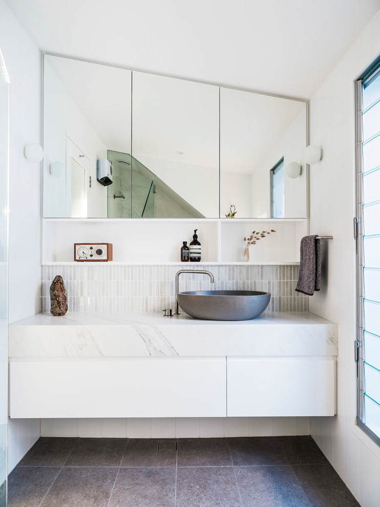 Mid-sized contemporary bathroom in Sydney with flat-panel cabinets, white cabinets, a one-piece toilet, white tile, ceramic tile, white walls, ceramic floors, a vessel sink, engineered quartz benchtops, grey floor, a hinged shower door and white benchtops.