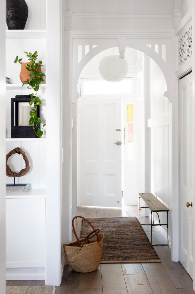 Diseño de hall costero de tamaño medio con paredes blancas, suelo de madera en tonos medios, puerta simple y suelo gris