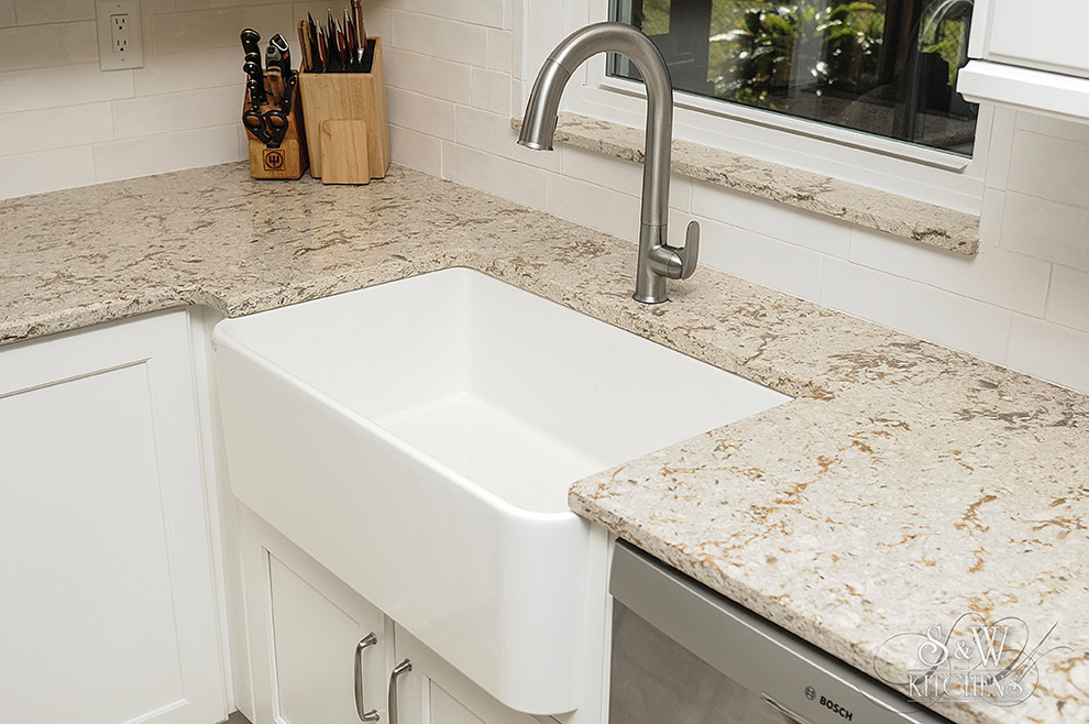 Example of a mid-sized transitional galley porcelain tile eat-in kitchen design in Tampa with a farmhouse sink, flat-panel cabinets, white cabinets, quartz countertops, white backsplash, subway tile backsplash, stainless steel appliances and a peninsula