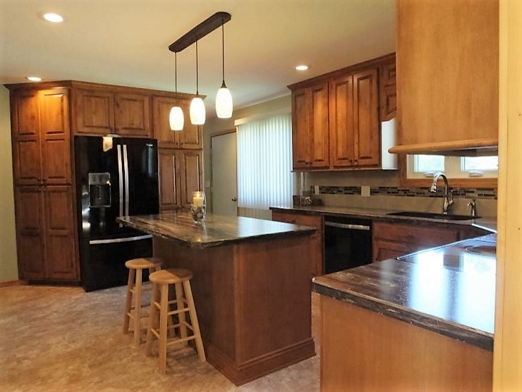 Inspiration for a mid-sized rustic u-shaped vinyl floor and beige floor open concept kitchen remodel with raised-panel cabinets, medium tone wood cabinets, laminate countertops, multicolored backsplash, black appliances, an island, an undermount sink and matchstick tile backsplash