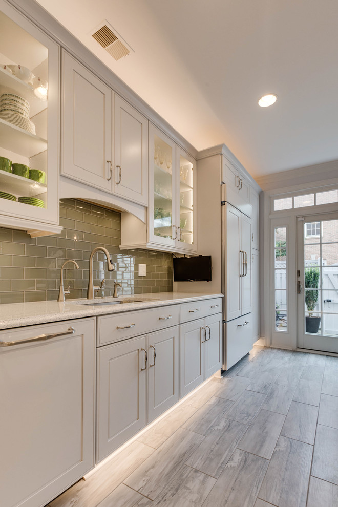 This is an example of a large transitional l-shaped kitchen in DC Metro with an undermount sink, raised-panel cabinets, quartz benchtops, green splashback, subway tile splashback and with island.