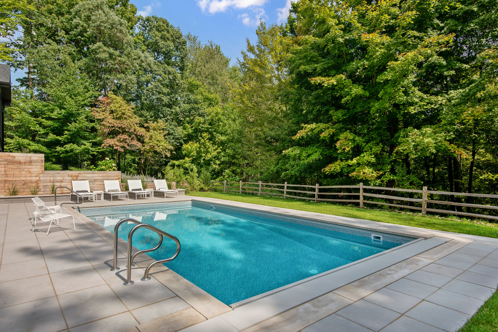 Mid-sized modern backyard rectangular pool with natural stone pavers.