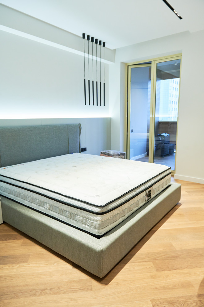 Пример оригинального дизайна: хозяйская, серо-белая спальня среднего размера: освещение в современном стиле с белыми стенами, полом из ламината, бежевым полом и обоями на стенах без камина