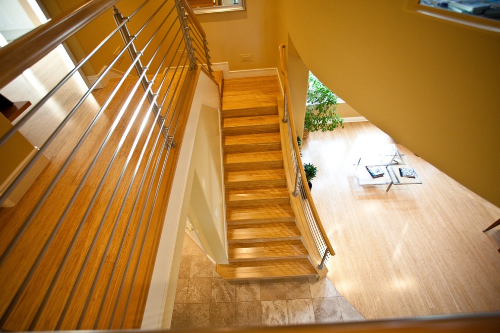 This is an example of a world-inspired wood curved wood railing staircase in Orange County with wood risers.