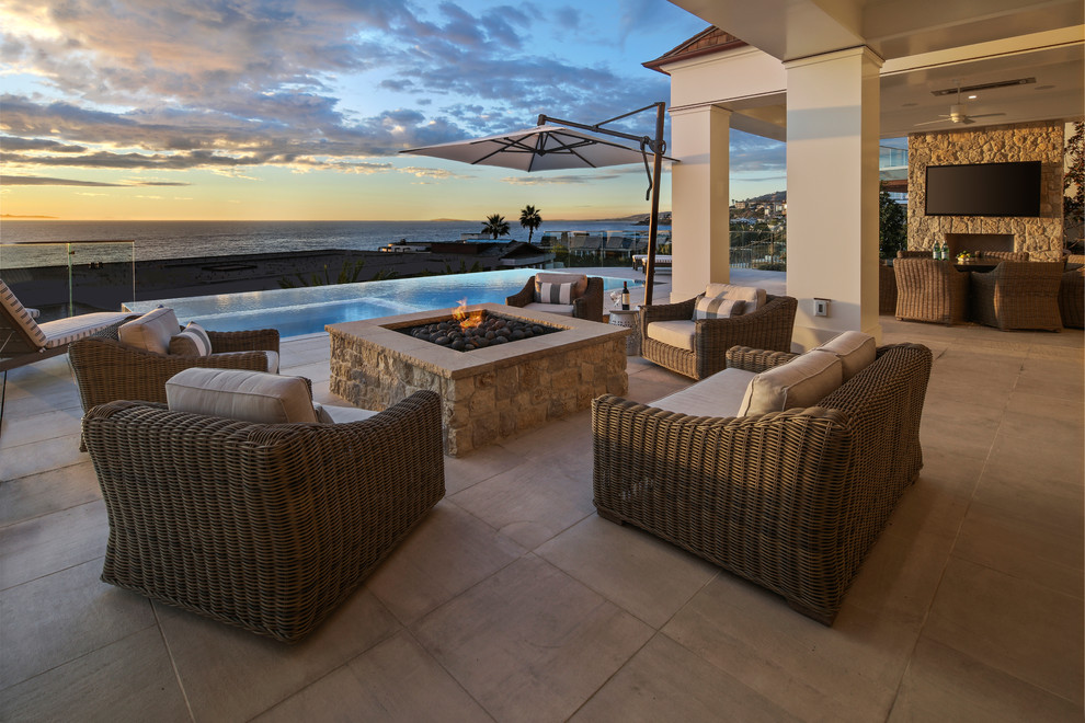 Inspiration for a beach style patio in Orange County with a fire feature and a roof extension.