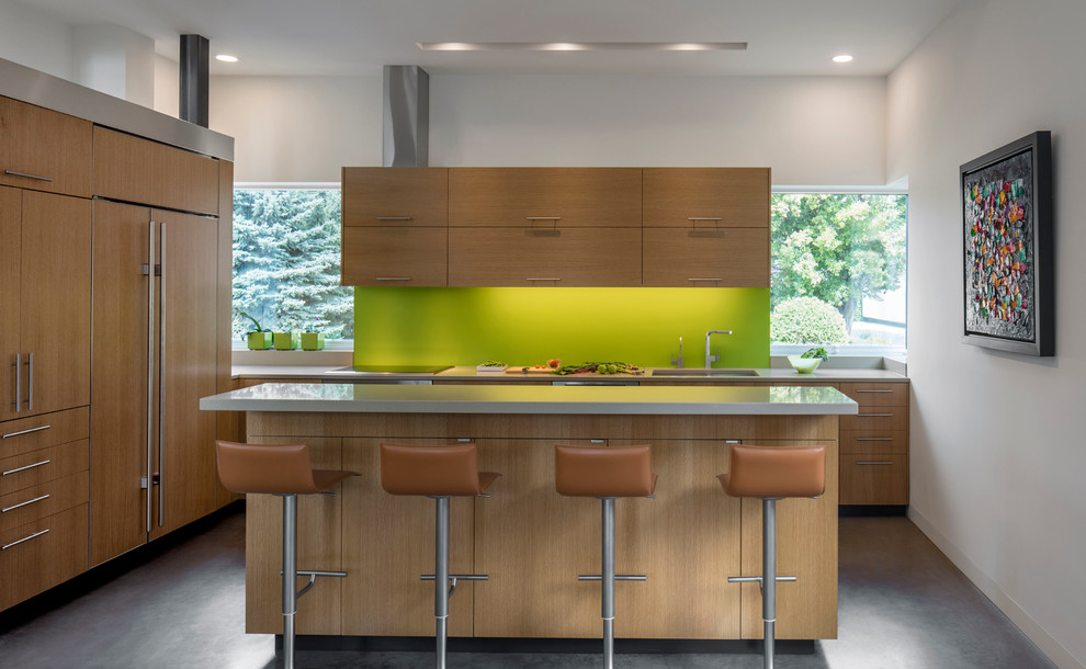 Design ideas for a mid-sized contemporary l-shaped open plan kitchen in Phoenix with a double-bowl sink, flat-panel cabinets, light wood cabinets, green splashback, panelled appliances, concrete floors, with island and grey floor.