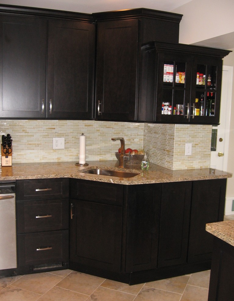 Photo of a small contemporary galley separate kitchen in Cincinnati with a single-bowl sink, shaker cabinets, dark wood cabinets, granite benchtops, yellow splashback, glass tile splashback, stainless steel appliances, porcelain floors and no island.