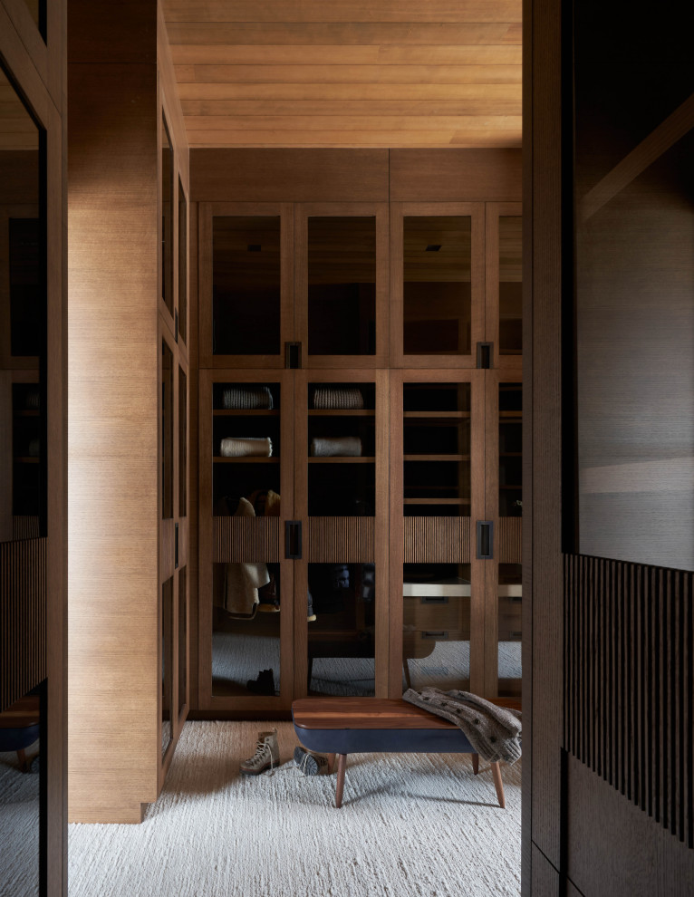 Immagine di un'ampia cabina armadio unisex minimalista con ante lisce, ante in legno scuro, moquette, pavimento beige e soffitto in legno