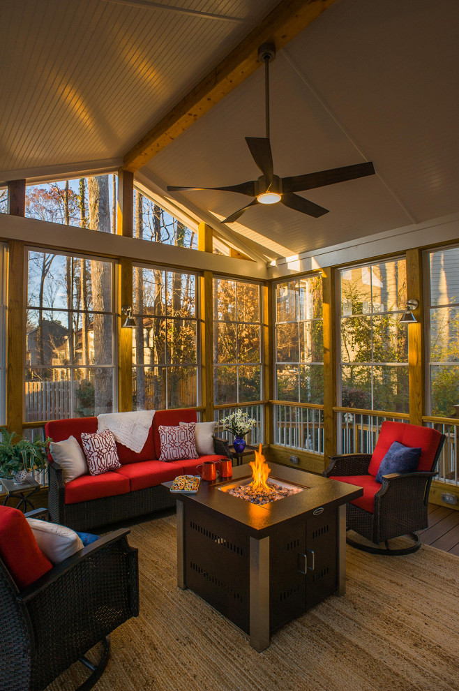 This is an example of a transitional backyard verandah in Atlanta with a fire feature, a roof extension and wood railing.