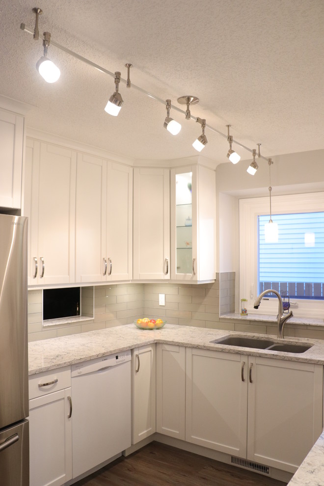 Small transitional u-shaped eat-in kitchen photo in Edmonton with an undermount sink, recessed-panel cabinets, white cabinets, quartz countertops, gray backsplash, glass tile backsplash, stainless steel appliances, no island and white countertops