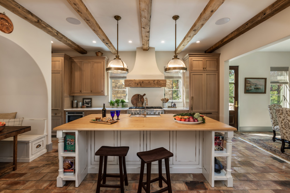 Inspiration for a large mediterranean kitchen in Other with a farmhouse sink, flat-panel cabinets, grey cabinets, wood benchtops, stainless steel appliances, terra-cotta floors, with island, pink floor and beige benchtop.