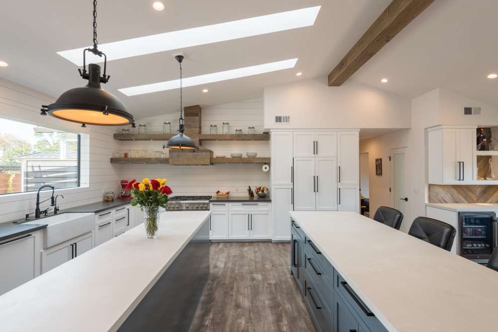 Kitchen - large transitional l-shaped medium tone wood floor kitchen idea with a farmhouse sink, shaker cabinets, white cabinets, paneled appliances, two islands and gray countertops