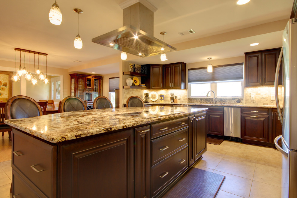 Large transitional l-shaped porcelain tile eat-in kitchen photo in Miami with an undermount sink, raised-panel cabinets, dark wood cabinets, granite countertops, beige backsplash, stone tile backsplash, stainless steel appliances and an island