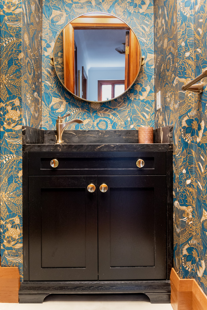Mid-sized transitional powder room in Toronto with shaker cabinets, black cabinets, a one-piece toilet, multi-coloured walls, porcelain floors, an undermount sink, marble benchtops, beige floor, black benchtops, a built-in vanity, wallpaper and wallpaper.