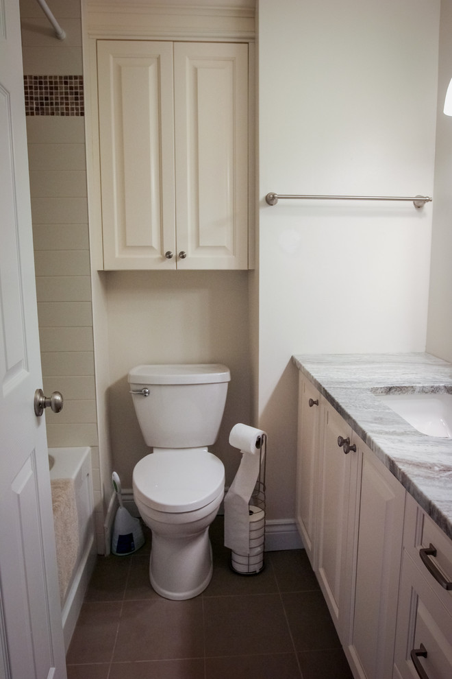Small traditional kids bathroom in Ottawa with raised-panel cabinets, white cabinets, a shower/bathtub combo, a two-piece toilet, gray tile, ceramic tile, grey walls, ceramic floors, an undermount sink and engineered quartz benchtops.