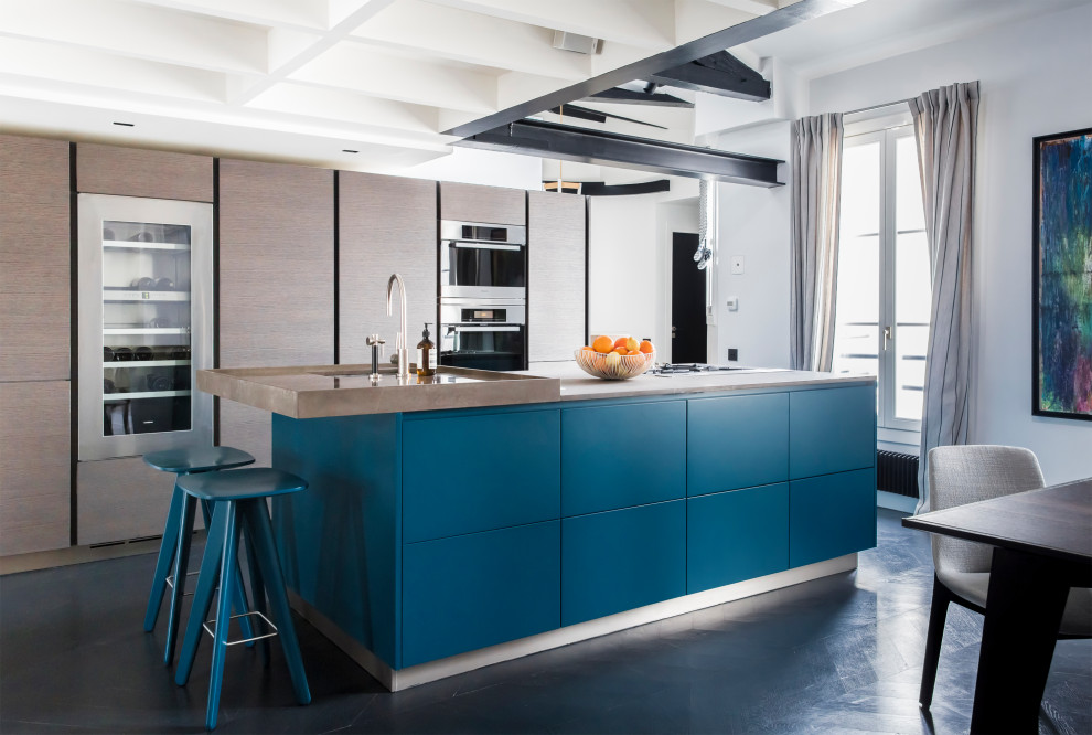 This is an example of a contemporary eat-in kitchen in Paris with an undermount sink, flat-panel cabinets, brown cabinets, stainless steel appliances, with island, black floor, brown benchtop and exposed beam.