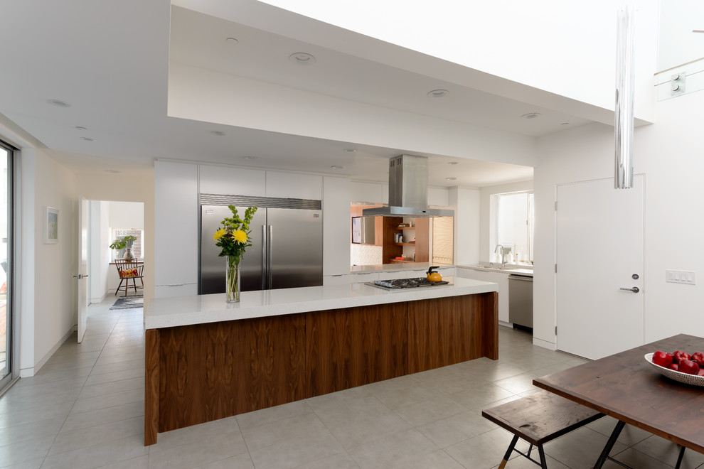 This is an example of a contemporary eat-in kitchen in Los Angeles with flat-panel cabinets, white cabinets and stainless steel appliances.