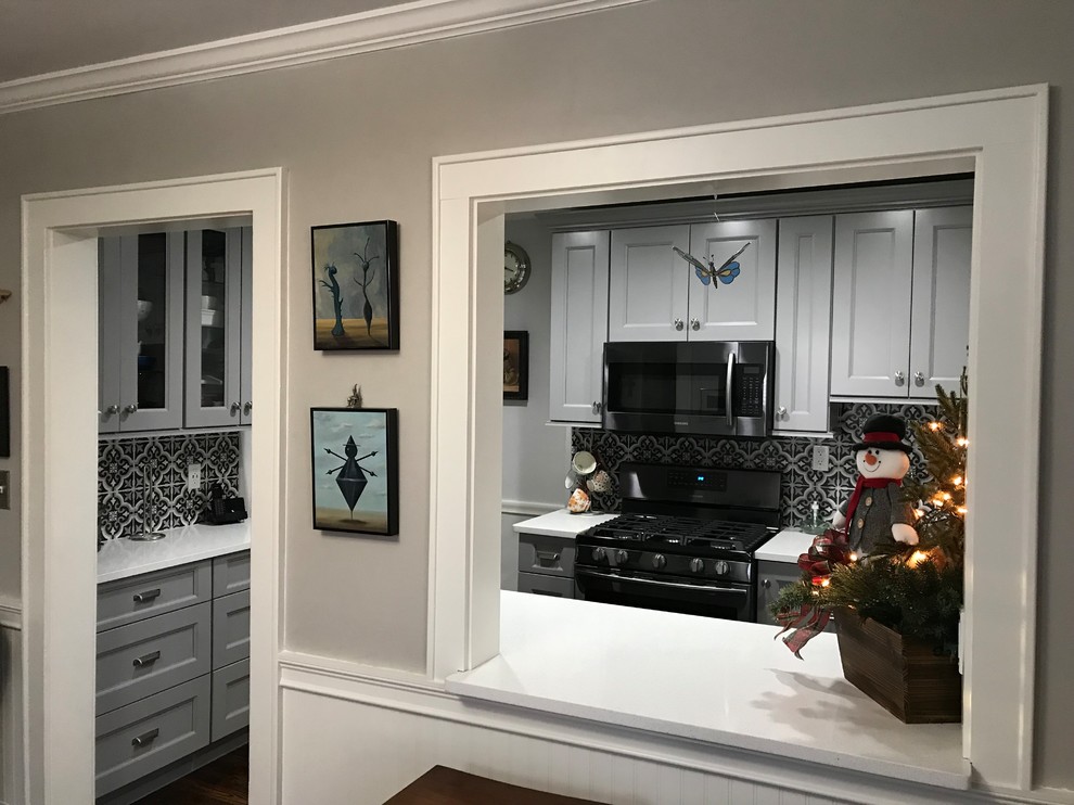 Inspiration for a small transitional galley medium tone wood floor and brown floor kitchen remodel with an undermount sink, shaker cabinets, gray cabinets, quartz countertops, multicolored backsplash, porcelain backsplash, black appliances and no island