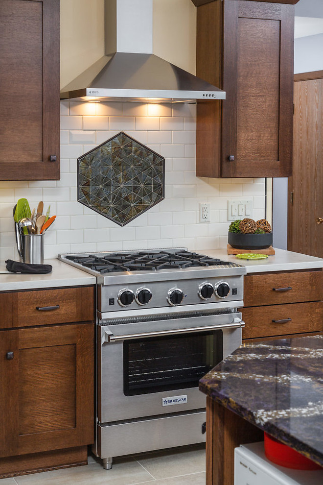 Example of a mid-sized transitional l-shaped open concept kitchen design with recessed-panel cabinets, dark wood cabinets, quartz countertops, white backsplash, subway tile backsplash, stainless steel appliances and an island